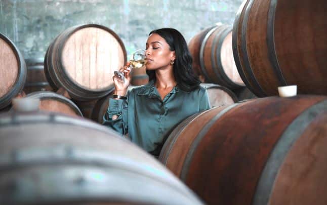 Vrouw die een glas chardonnay proeft in de kelder van een wijnmakerij